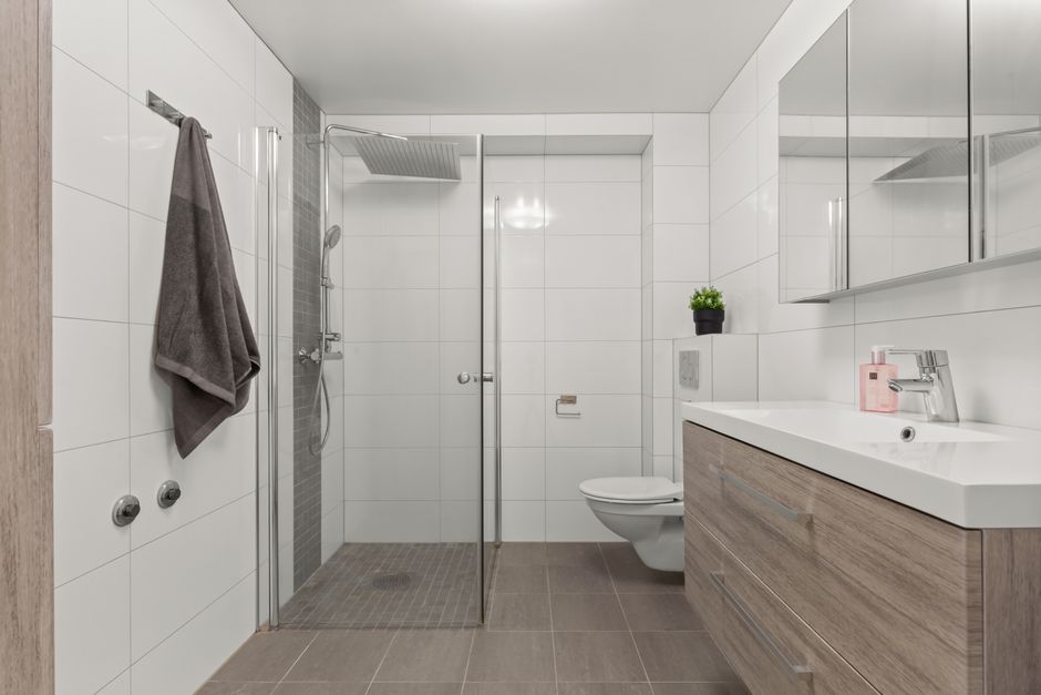 Salle de bain lumineuse avec douche de plain-pied, paroi vitrée et WC suspendu